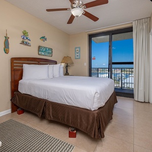 Enjoy restful nights in this guest bedroom featuring a queen bed, coastal decor, and balcony access with a view
