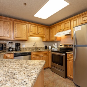 Warm wooden cabinetry complements the granite countertops in this inviting kitchen, featuring stainless appliances