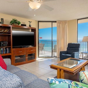 Living area features a cozy blue sofa with queen sleeper, two recliners, coffee table, and a stunning beach view
