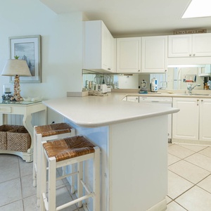 Gather around the kitchen bar with friends for casual meals, surrounded by bright cabinetry and inviting decor