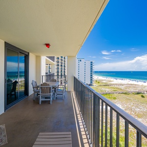 Spacious balcony with a dining table offers panoramic views of the beach and vibrant blue gulf waters