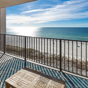 Enjoy the fresh air from the balcony with comfortable seating and views of the shimmering water and beach below