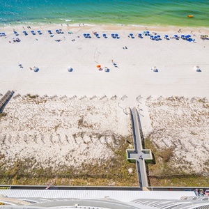 Soft green water laps gently at the shore as colorful umbrellas create a festive scene along the bright sand