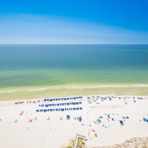 Breathtaking view of the beach dotted with colorful umbrellas under a clear blue sky, perfect for a relaxing getaway