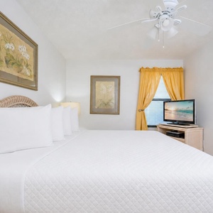 Clean white linens cover the bed in the king suite where soft ceiling fan breezes keep you comfortable
