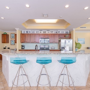 Modern kitchen with sleek granite countertops, stainless appliances, and stylish blue bar stools
