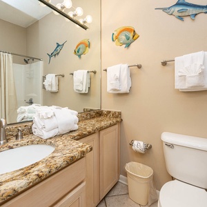 Brightly decorated guest bathroom featuring a spacious granite countertop, plush towels, and colorful fish art on the walls