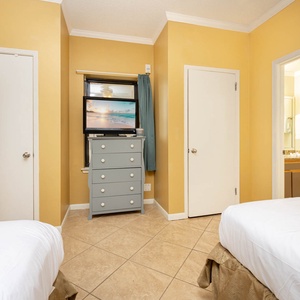 Two double beds and a dresser with a TV, creating a cheerful atmosphere in this cozy guest room