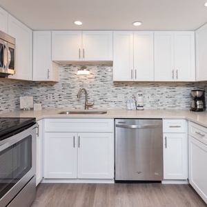 Bright white cabinetry and a sleek countertop enhance this kitchen, featuring modern appliances and a stylish backsplash
