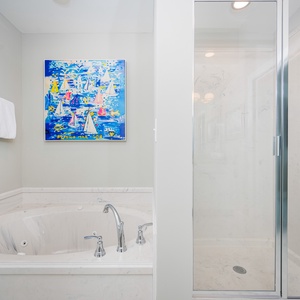 Indulge in relaxation with a jetted tub and a colorful nautical artwork enhancing the master bathroom atmosphere