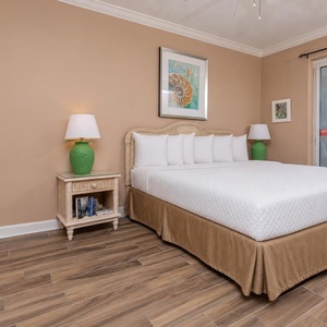 The master bedroom features a king bed, vibrant green lamps, and a balcony offering a stunning beach front view