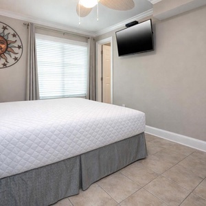 This cozy bedroom features a comfortable bed, a TV for entertainment, and a charming sun-themed wall decor