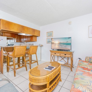 Living area featuring tropical decor, a flat-screen TV, and a cozy rattan seating arrangement with queen sofa-sleeper