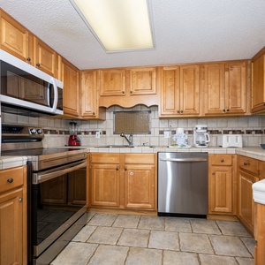 Warm wood cabinetry complements the modern appliances in this inviting kitchen, featuring ample counter space for meal prep