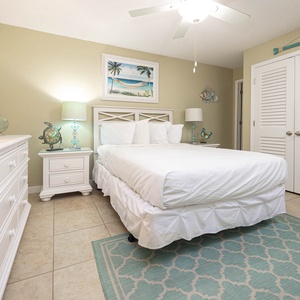 The guest bedroom features soft bedding, a queen bed, beach decor, and a calming color palette, perfect for relaxation