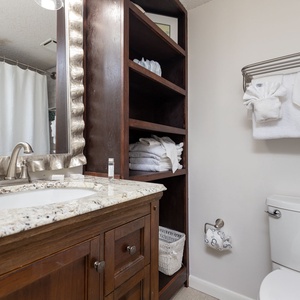 Refresh in this stylish guest bathroom featuring a granite countertop, elegant mirror, and ample storage