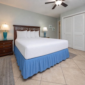The guest bedroom features a comfortable queen bed with crisp linens, accented by a blue skirt and stylish decor