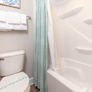 Enjoy a relaxing shower after a day at the beach in this guest bath with stylish accents and fluffy towels