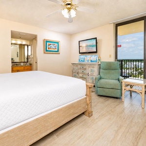 The bright master bedroom features a king bed adorned with plush white linens, complemented by elegant bedside lamps and art