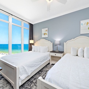 Wake to gulf light and on plush queen beds while panoramic windows frame the beach in this guest room