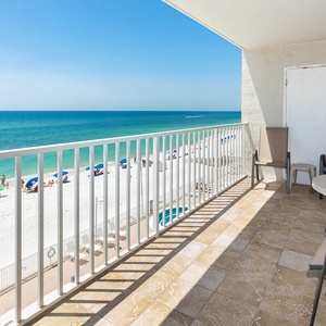 Enjoy a stunning beach view from this balcony, featuring comfortable seating and a perfect spot for relaxation