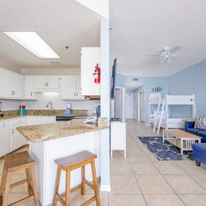 The modern kitchen features stainless appliances, granite countertops, and a cozy breakfast bar with wooden stools