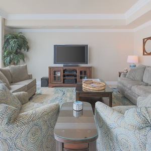Relax in this spacious living area with comfortable seating, a large TV, and vibrant decor for your enjoyment