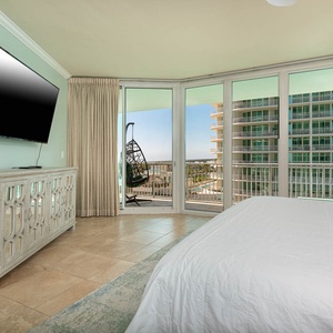 The master bedroom features a large TV, stylish decor, and a cozy balcony with a hanging chair for relaxing views