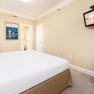 Relaxing guest bedroom featuring a plush king bed, tasteful decor, and a wall-mounted TV
