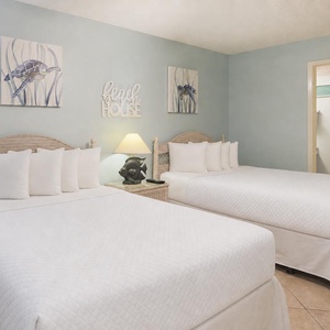 Cheerful guest bedroom with two double beds, beach decor, and soft lighting for a restful atmosphere