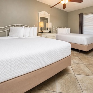 Rest in the inviting guest bedroom featuring two queen beds, soft lighting, and a stylish dresser for your convenience