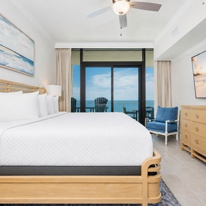 Relax in the master suite featuring a plush king bed, large TV, and beachfront balcony access