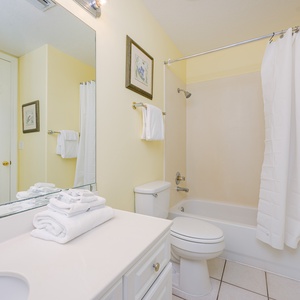 Soft yellow walls brighten the guest bath as you refresh with a warm shower behind the white curtain
