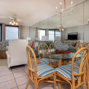 Bright dining area features a glass table with striped chairs, complemented by gulf views through expansive windows