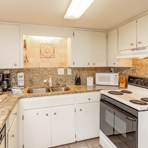 The kitchen features granite countertops, white cabinetry, and essential appliances, perfect for preparing meals