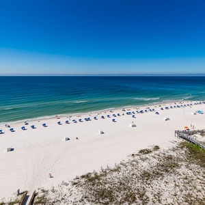 Expansive beachfront view showcasing vibrant umbrellas and sunbathers on the soft white sand, inviting relaxation and fun