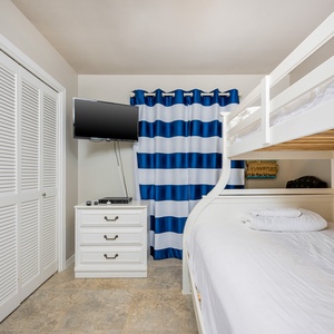 This cozy bedroom features a stylish bunk bed, a mounted TV, and vibrant striped curtains, perfect for a fun stay