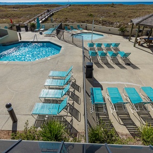 Pool area featuring a kiddie pool, turquoise loungers, and a scenic view of the beach, inviting relaxation and sunbathing