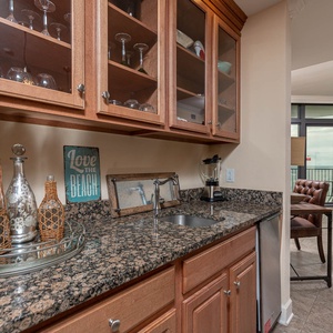This stylish wet bar features elegant glassware and a stylish granite countertop, perfect for entertaining with a beach view