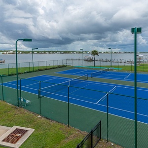 Enjoy a vibrant view of the blue tennis courts alongside the serene lagoon, perfect for active relaxation