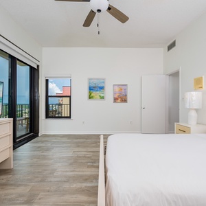 Bright guest bedroom featuring a queen bed, modern decor, and stunning views through the balcony doors