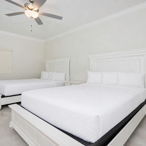 Relax in this guest bedroom featuring two comfortable queen beds, soft linens, and a ceiling fan for a refreshing stay