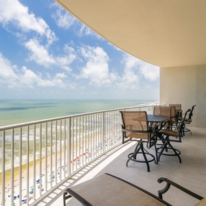 Savor meals or drinks on the spacious balcony, surrounded by comfortable seating and expansive views of the beach