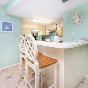 Inviting kitchen area with white cabinetry, a cozy breakfast bar, and cheerful aqua walls
