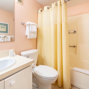 Bright and inviting guest bath featuring a yellow shower curtain, modern fixtures, and complimentary toiletries for guests