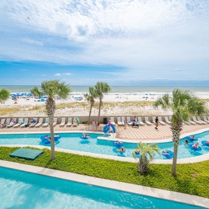 Enjoy the lazy river area with palm trees and a beautiful view of the pristine beach and colorful umbrellas in the distance