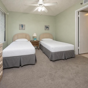 This guest room features two twin beds, soft beige walls, and a cozy atmosphere enhanced by natural light from the window