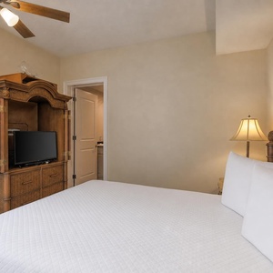 This cozy bedroom features a comfortable bed, a TV for entertainment, and warm wood accents, creating a relaxing retreat