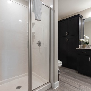 Enjoy a relaxing shower after a day at the beach in this guest bath with stylish cabinetry and spacious vanity