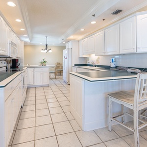 Open and spacious kitchen design, featuring white cabintery and appliances, and additional counter space